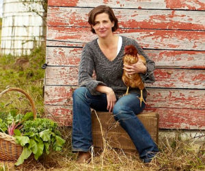 woman sits holding a chicken