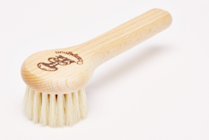 A round wooden brush with course bristles and a handle.