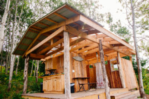 A wooden structure equipped with electricity and light, seasonal plumbing for 2 flush toilets, 2 hot showers, and a simple rustic camp kitchen stocked with dishes, 2-burner propane stove, and basic cooking amenities.