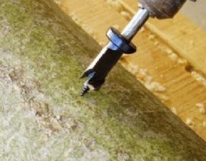 A close-up image of an angle grinder drill bit about to drill a hole in a log.