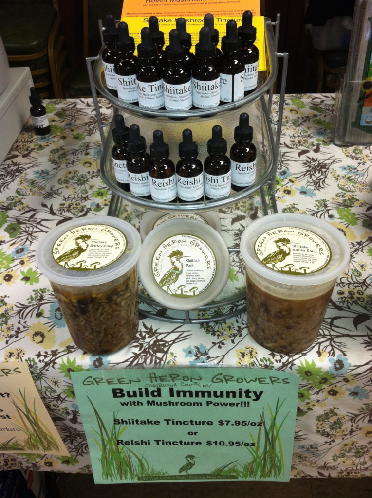 Shiitake tinctures on a display rack, with containers of shiitake barley soup in front of them.
